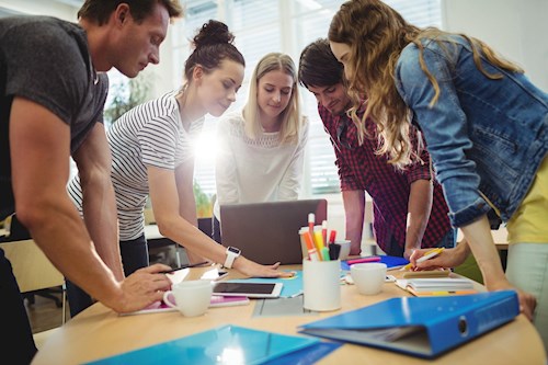 People gathered around a table, looking at a laptop