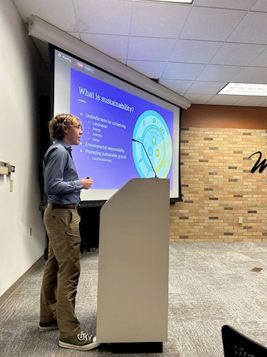 blonde man standing in front of powerpoint