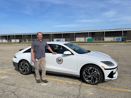 Public Works director standing in front of white electric car