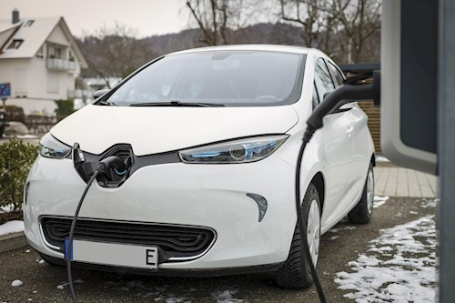 Woman plugging an electric vehicle into a charger